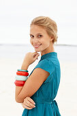 A young blonde woman on a beach wearing a blue summer dress