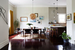 Open living room with dark floor and dining table in front of the kitchen