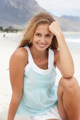 A young blonde woman on a beach wearing a light-blue top