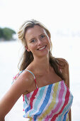 A young blonde woman on a beach wearing a light-blue top