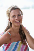 A young blonde woman on a beach wearing a light-blue top