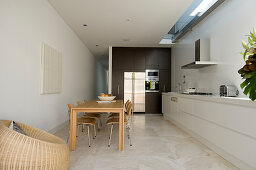 Wooden dining table and chairs next to long white kitchen counter