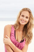 Junge Blonde Frau im rosa Top und Bikini am Strand