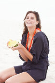 Brünette Frau im lila Strandkleid mit Melone