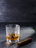 Crystal glass with whiskey drink and thick cigar
