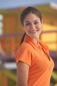 A young brunette woman wearing an orange polo shirt
