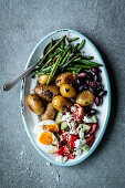 Antipasti platter with beans, potatoes, olives, egg and Greek salad