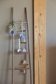 Handcrafted wooden ladder holding flower arrangements and garland of paper boats