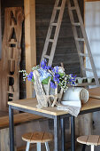 Summer flowers in zinc bucket enclosed in pieces of driftwood and hessian ribbon