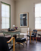 Black leather chairs, matching stool with cow-horn legs stool and white easy chair around rustic table