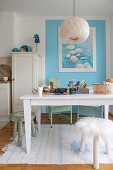 Weißer Tisch und Hocker vor hellblauer Wand in offener Küche