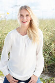 A young blonde woman wearing a white blouse