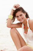 A brunette woman on a beach wearing a white top and shorts