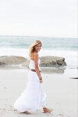 Blond Frau in weißem Sommerkleid am Meer
