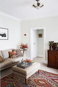 Upholstered sofa and matching upholstered table in beige on kilim