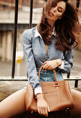 A young brunette woman wearing a blouse and a mini skirt with a bag