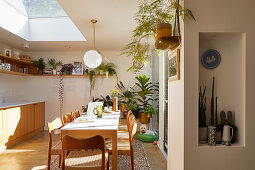 Esstisch mit Stühlen in offener Küche mit Oberlicht