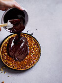 Salted-Caramel-Macadamia-Tarte mit Schokoladenganache bestreichen