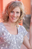 A blonde woman wearing a grey spotted blouse