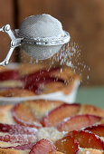 Baking of plum pie with almond frangipane, plumpie icing sugar