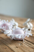 Easter eggs in handmade paper nests on wooden surface