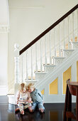 Elegant staircase with white stairs and dark wooden floor, children reading on the floor