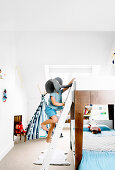 Bunk bed in white children's room, boy on bed ladder