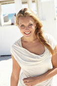 A blonde woman on a beach wearing a beige summer dress