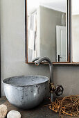 Vintage tap fitting and metal basin below mirrored cabinet in bathroom