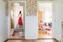 View from hallway into living room and of a woman walking up stairs