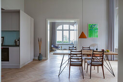 Dining table with slender lines and chairs in open-plan interior with kitchen in custom-made cube