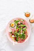 Salad with fava beans, dried tomatoes, ham and soft-boiled eggs