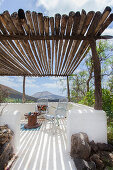 White-painted terrace below rustic pergola