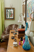 Assorted collection of boxes on top of console table in bedroom with leopard print armchair