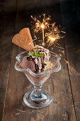 Chocolate ice cream sundae with chopped nuts and sparklers