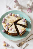 Easter carrot cake decorated with mini eggs and nutmeg with bunnies in the background