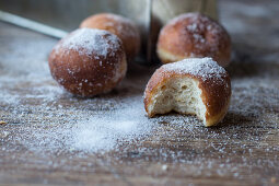 Fresh beignets near set of baked loaf in craft paper with powdered sugar