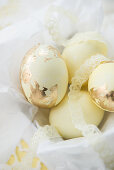 Pale yellow Easter eggs with gold leaf and lace ribbons