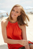 Blonde Frau in orangefarbenem Top am Strand