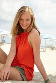 Blonde Frau in orangefarbenem Top am Strand