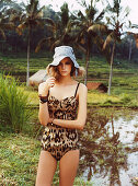 A young blonde woman wearing a tiger-patterned bathing suit and a hat
