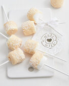 Marshmallows on sticks with white chocolate and sugar sprinkles