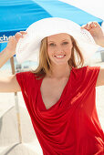 Blonde Frau mit weißem Hut in rotem Top am Strand