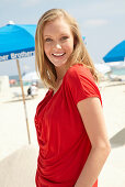 A blonde woman on a beach wearing a red top