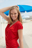 A blonde woman on a beach wearing a red top