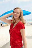 A blonde woman on a beach wearing a red top