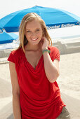 A blonde woman on a beach wearing a red top