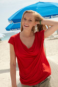 A blonde woman on a beach wearing a red top