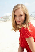 A blonde woman on a beach wearing a red top