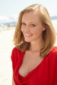 A blonde woman on a beach wearing a red top